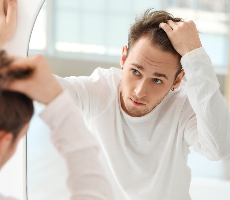 Man examining his thinning hairline in a mirror